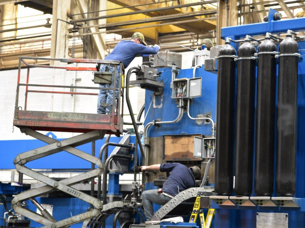 Two Butech Bliss large assembly equipment technicians work on a stretch leveler also used in the processing of steel.